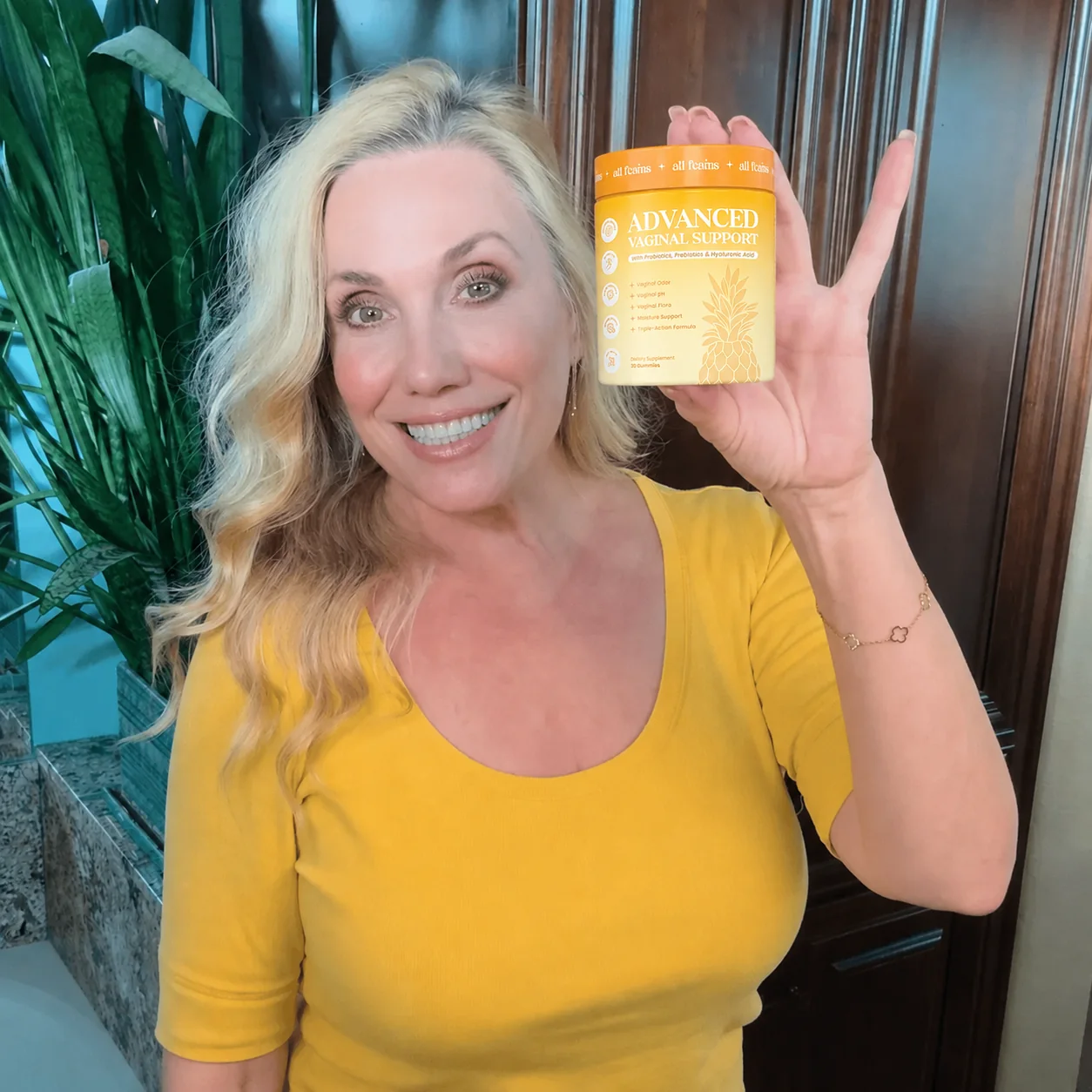 A smiling woman holds up her jar of Flora+.