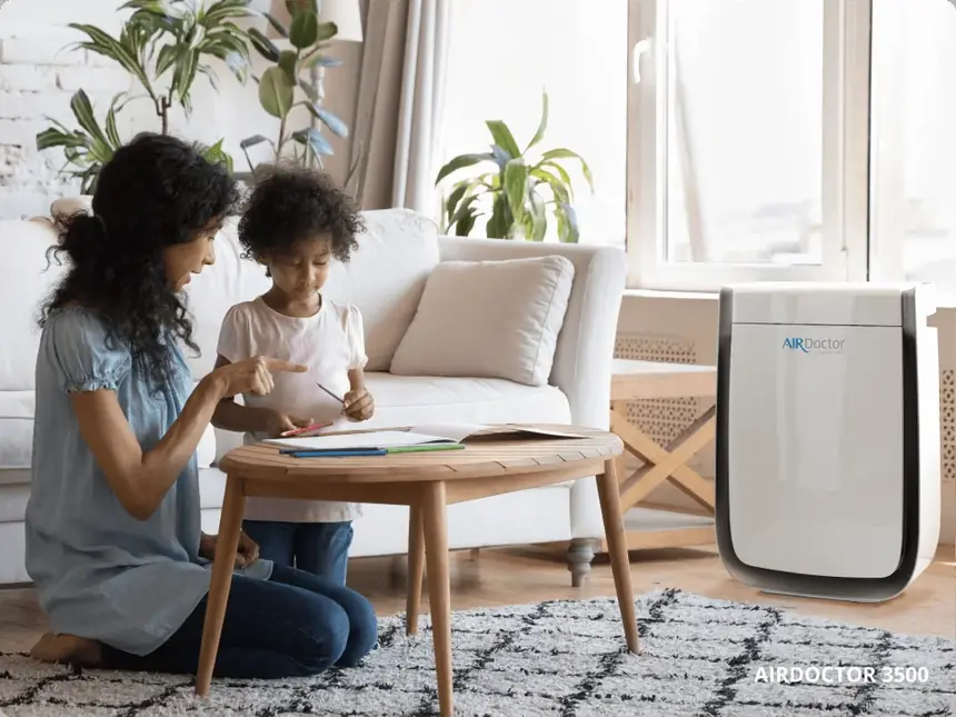 Parent and child in a living room with an AirDoctor purifier running nearby
