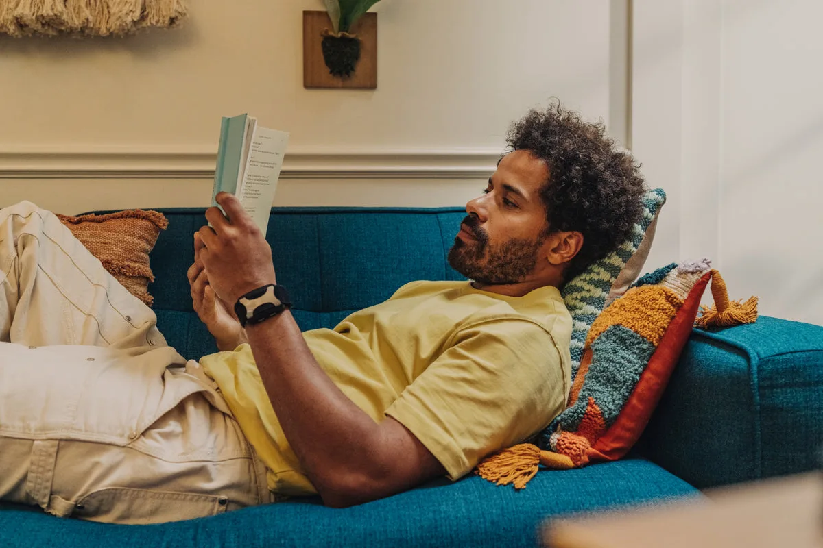 A person relaxing on a couch reading a book