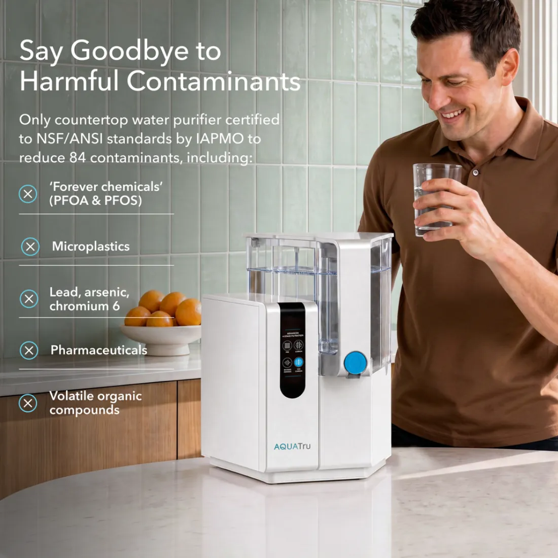 A man drinking a glass of water beside an AquaTru Classic purifier on a kitchen counter