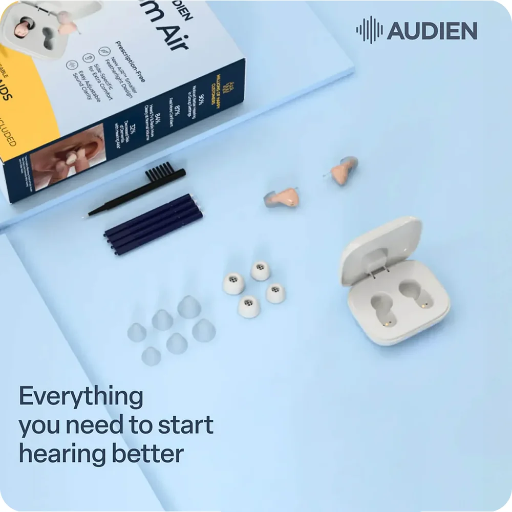 Flat lay of everything in the Atom Air box: the retail carton, a cleaning brush, wax guard sticks, several sizes of silicone domes, the pair of hearing aids and the white charging case