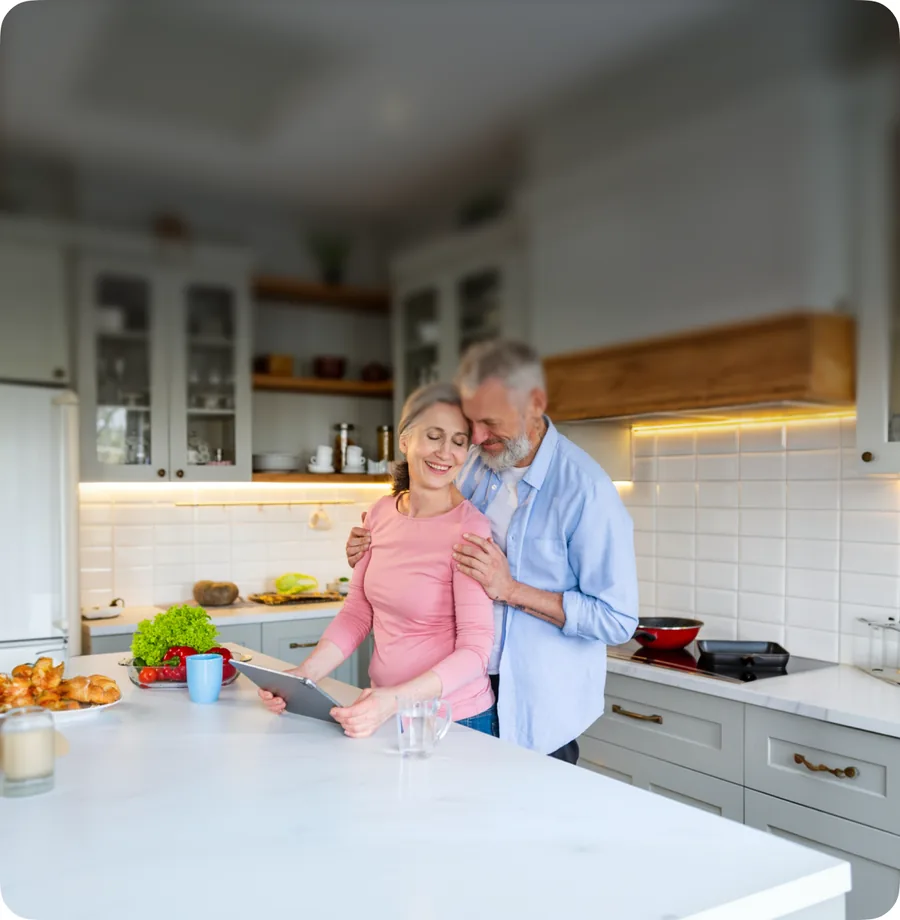 An older couple cooking together in a bright kitchen, talking