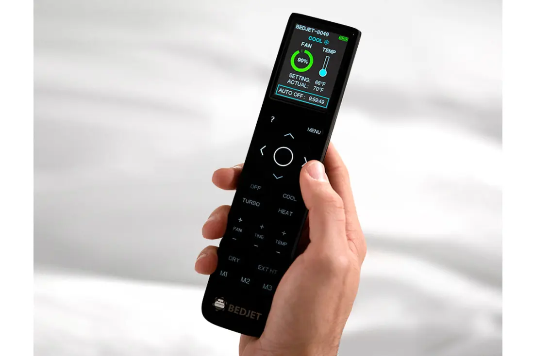 A hand holding the BedJet color screen remote control.