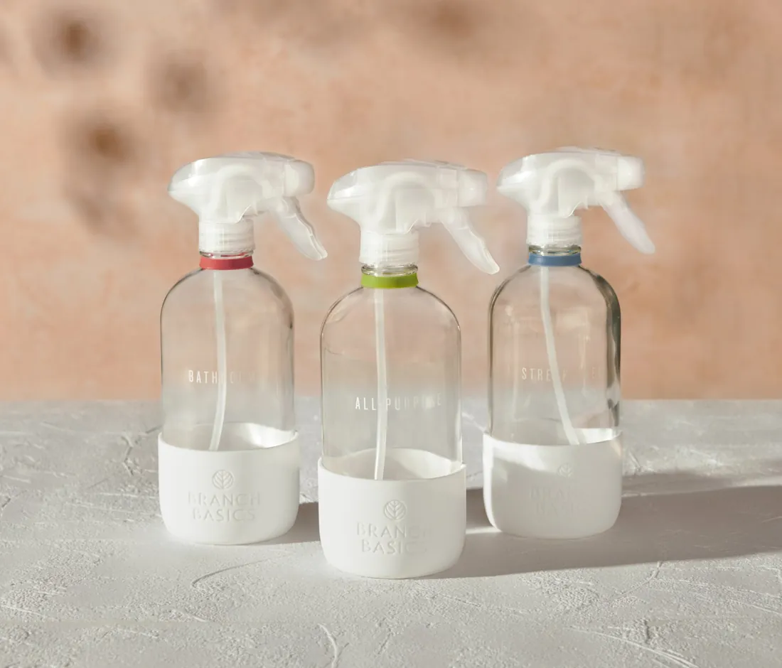 Three glass Branch Basics spray bottles with coloured caps for different dilutions
