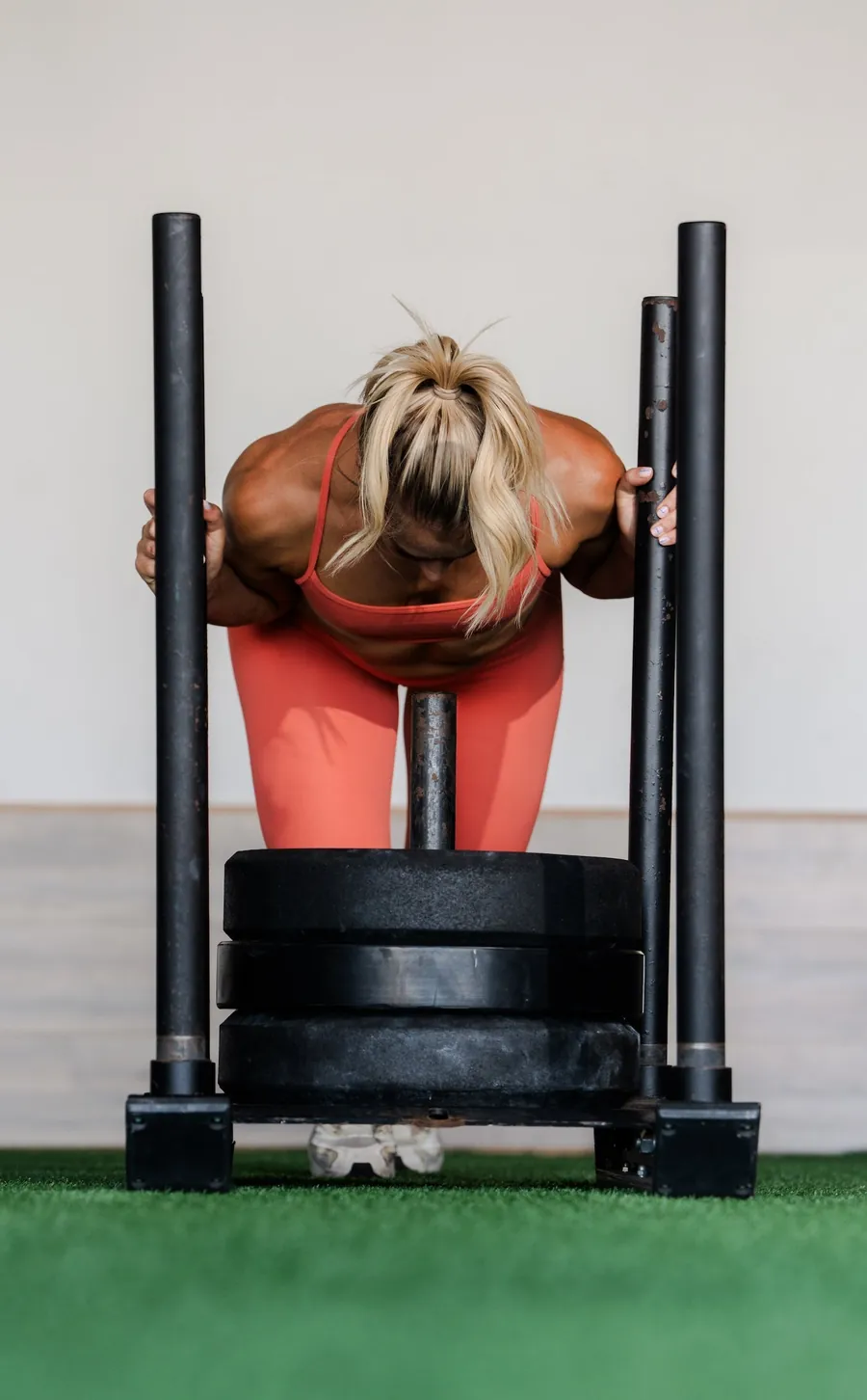 An athlete pushing a weighted sled on turf.
