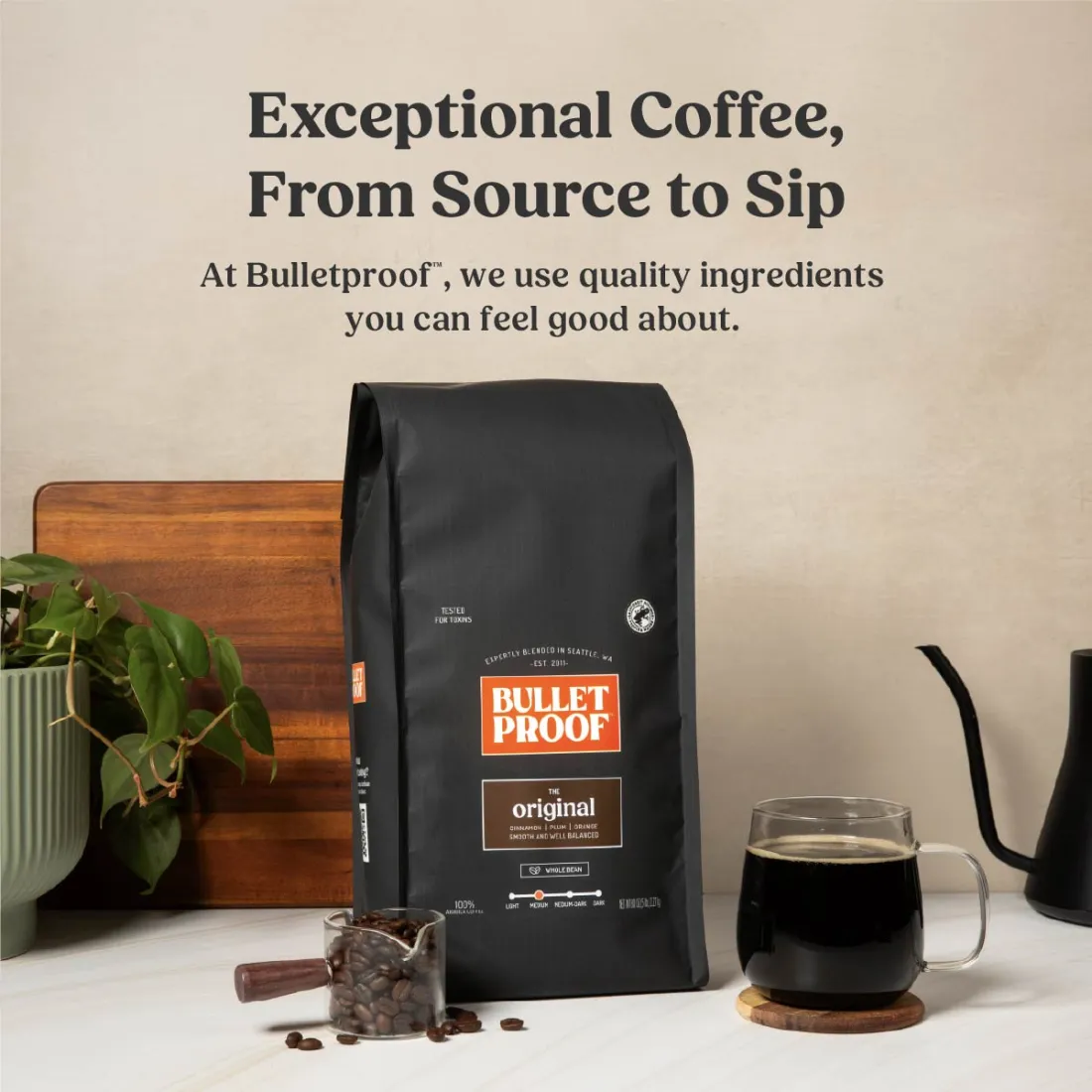 Bulletproof coffee bag beside a brewed cup and a pour-over kettle.