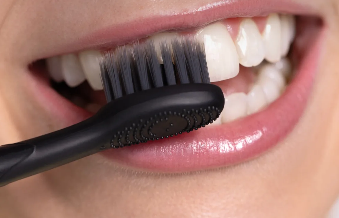 Close up of soft tapered black bristles resting against the gumline of the upper teeth