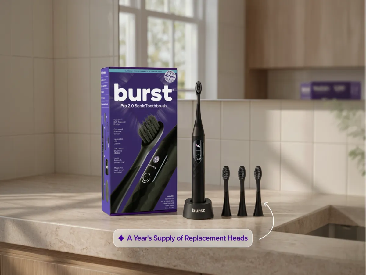 BURST Pro 2.0 sonic toothbrush on its charging base beside its box and three replacement heads on a bathroom counter
