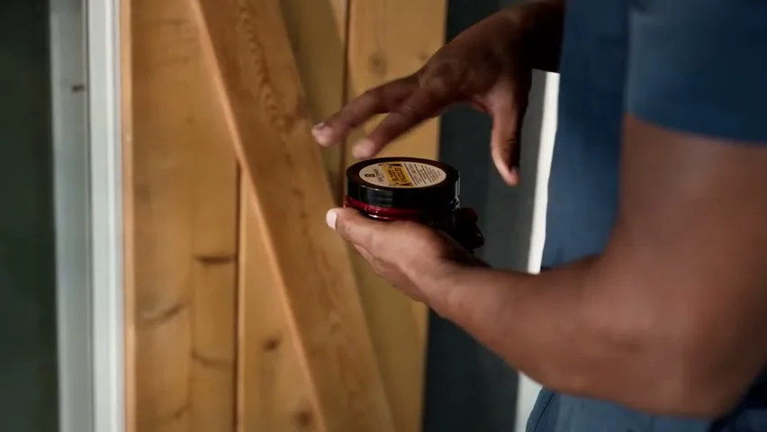 A worker opening a tub of Duke Cannon Bloody Knuckles Hand Repair Balm on a job site