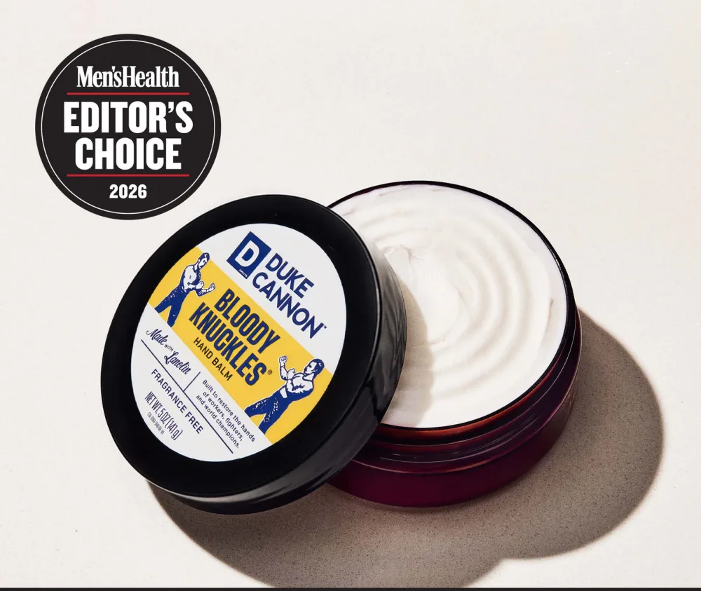 Open tub of Bloody Knuckles Hand Repair Balm showing the white balm, with a Men's Health Editor's Choice 2026 badge