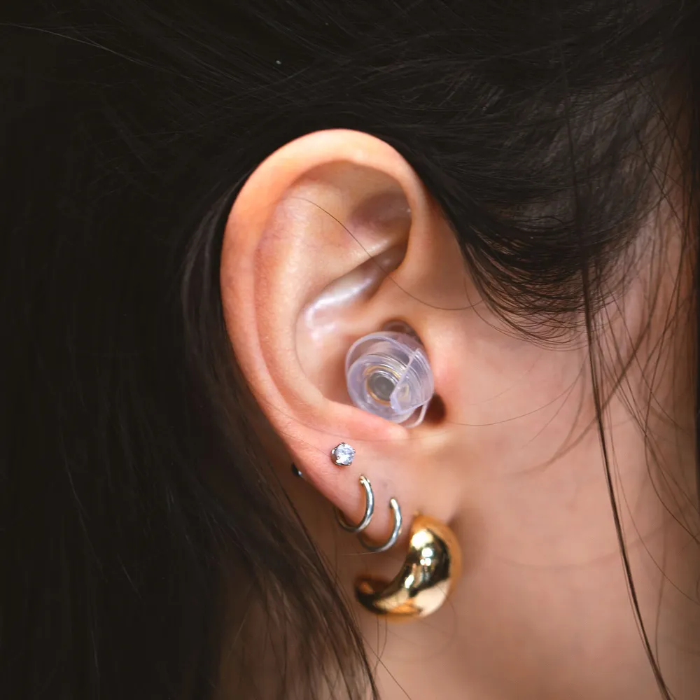 Close up of an ear wearing a transparent filtered earplug
