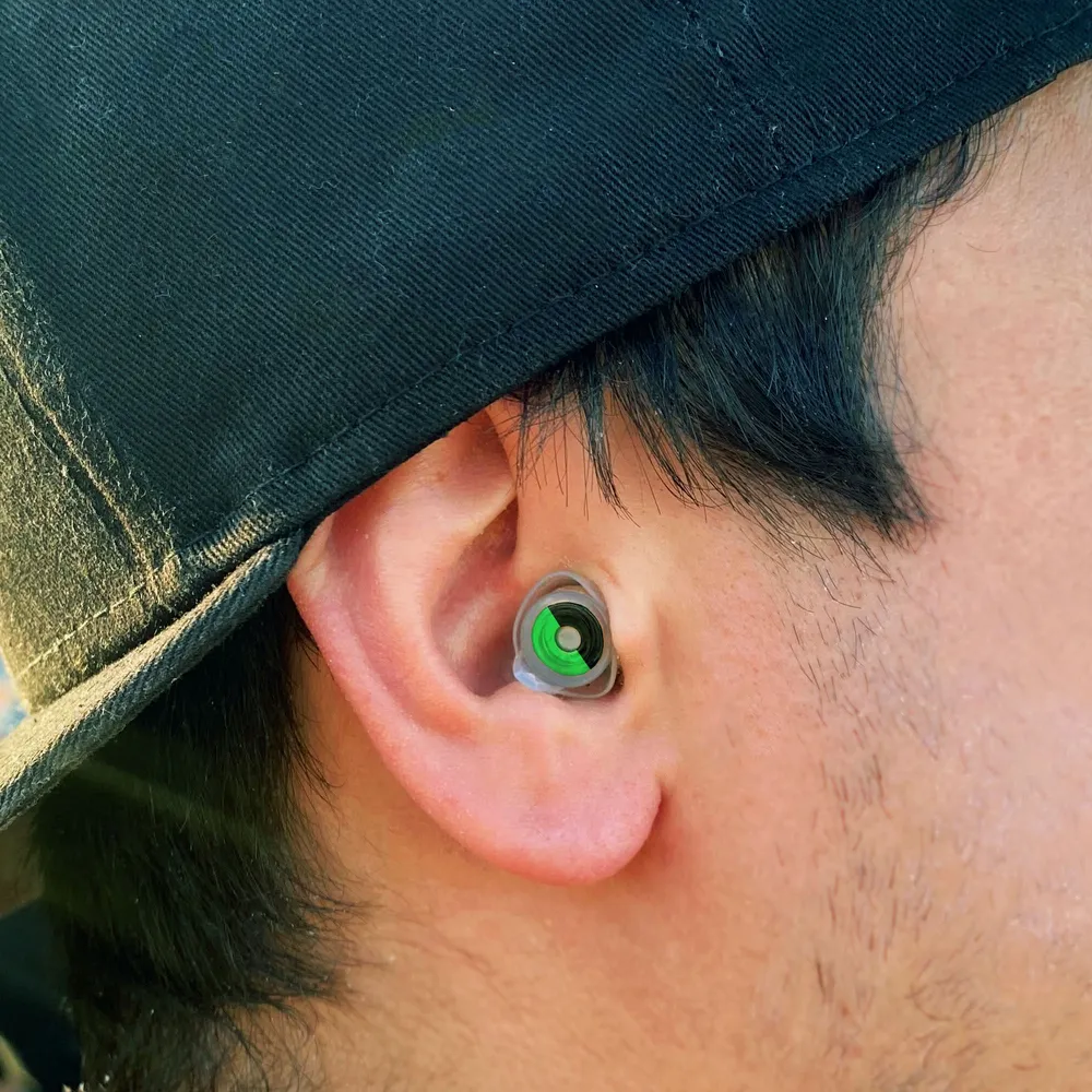 A filtered earplug worn under a cap at a festival