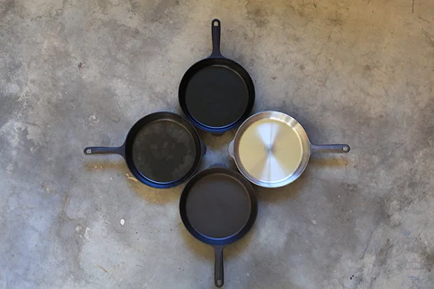 Four cast iron skillets photographed from above arranged like a clock face, showing four stages of seasoning from bare silver iron to glossy black