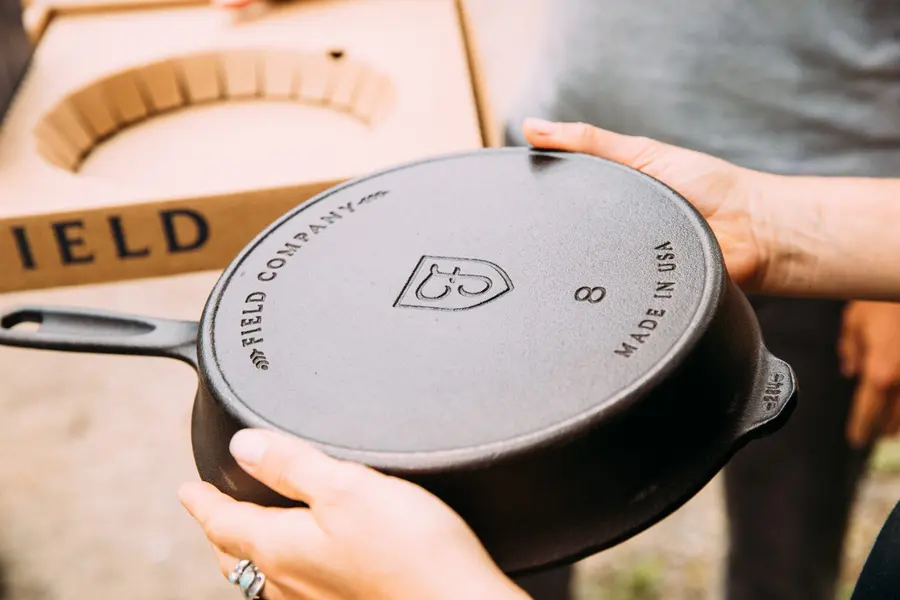 Hands lifting a new Field skillet out of its box