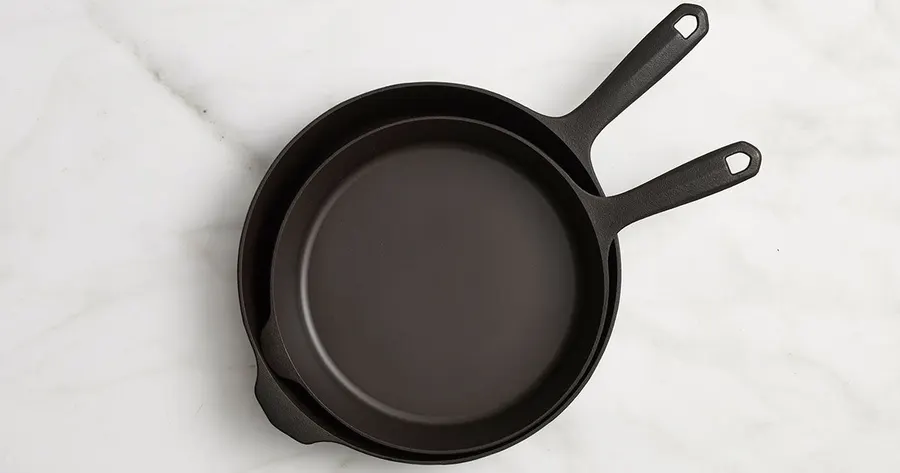 Two Field cast iron skillets stacked on a marble surface, seen from above