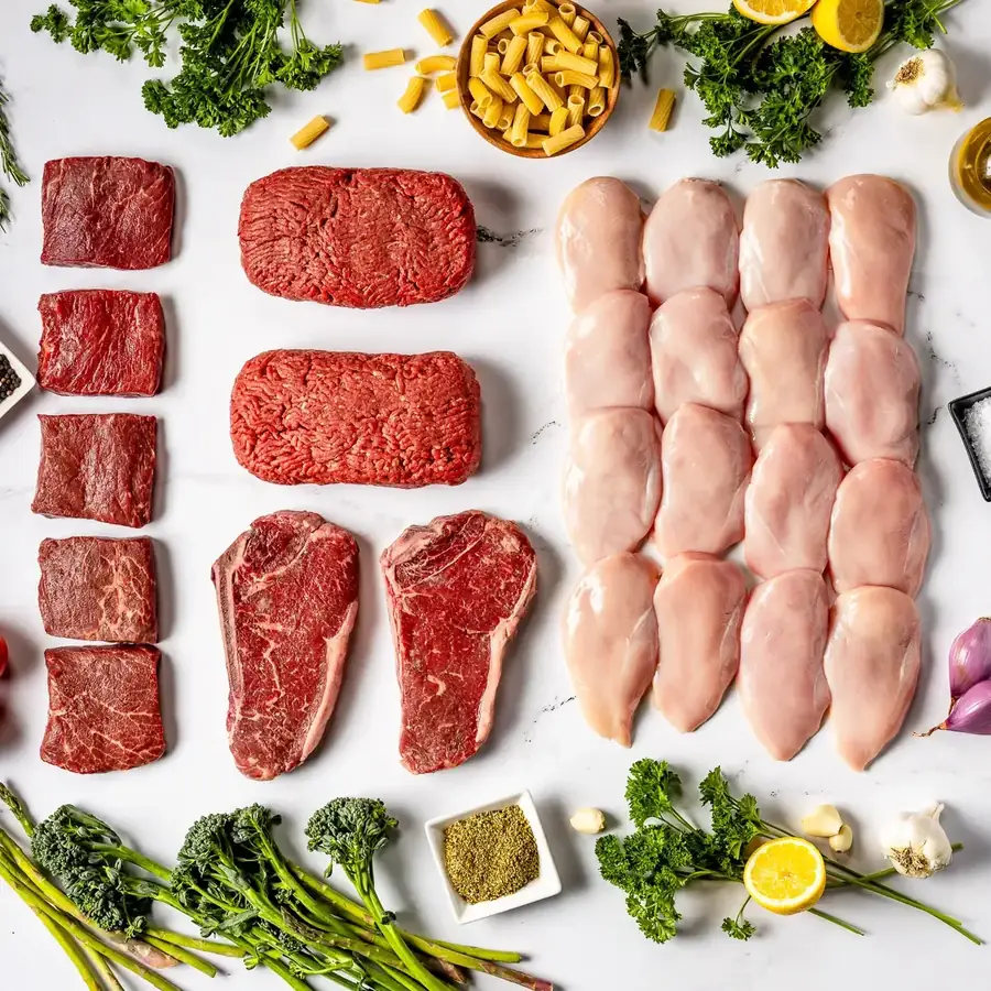 The Ranchers Classic box contents laid out: New York strips, flat iron steaks, ground beef and chicken breasts