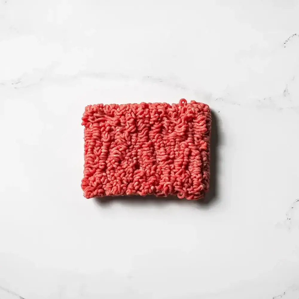 A one pound block of fresh ground beef on a white marble surface