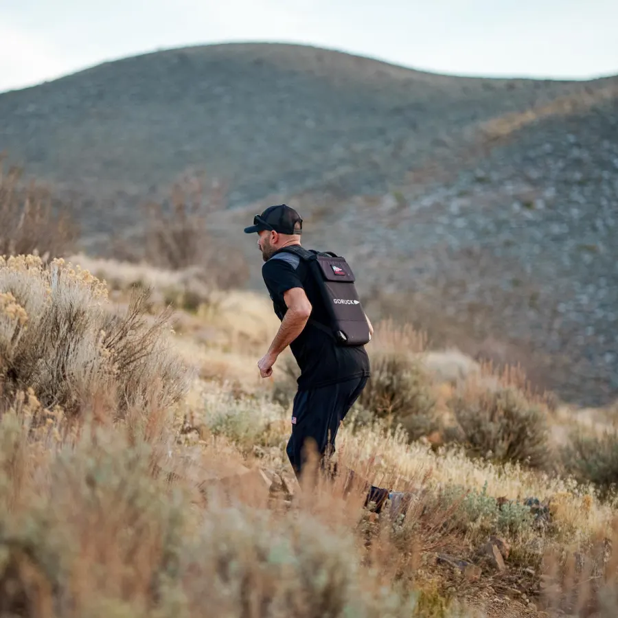 A man walking uphill on a desert trail with a loaded rucksack