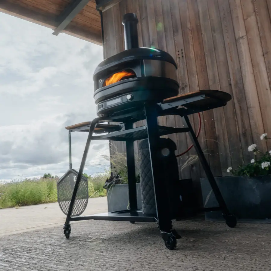 A Gozney Dome (Gen 2) oven on its stand in a paved outdoor space.