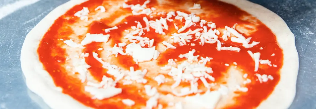 A topped raw pizza resting on a lightly floured surface, ready to be launched into the oven.