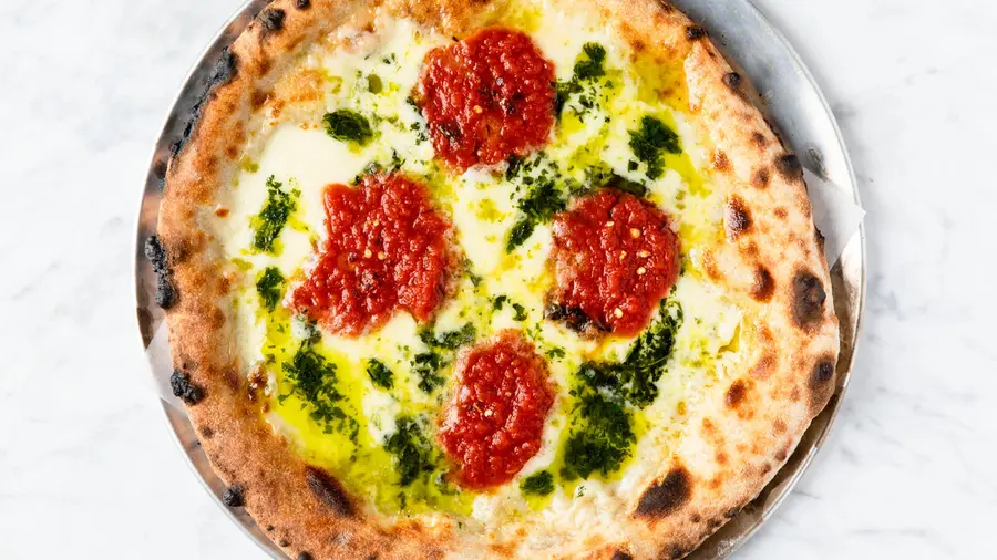 A finished Margherita pizza with basil, seen from above.