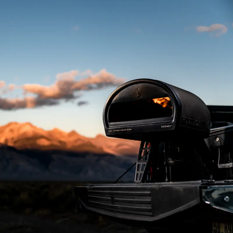 A black Gozney Roccbox set up outdoors at dusk.