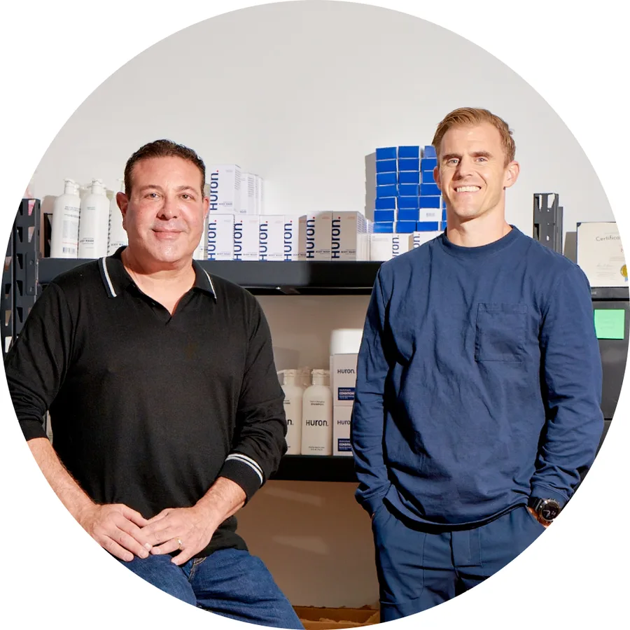 The two Huron co-founders standing in front of shelves of Huron product