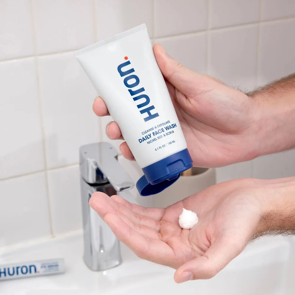 Hands dispensing Huron face wash at a bathroom sink