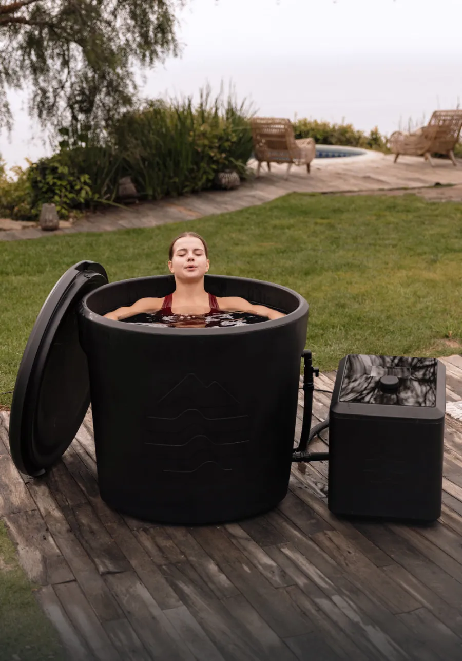 A woman seated upright inside an Ice Barrel with the water at her neck