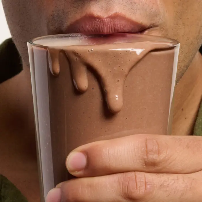 Close-up of a person drinking a chocolate shake from a glass