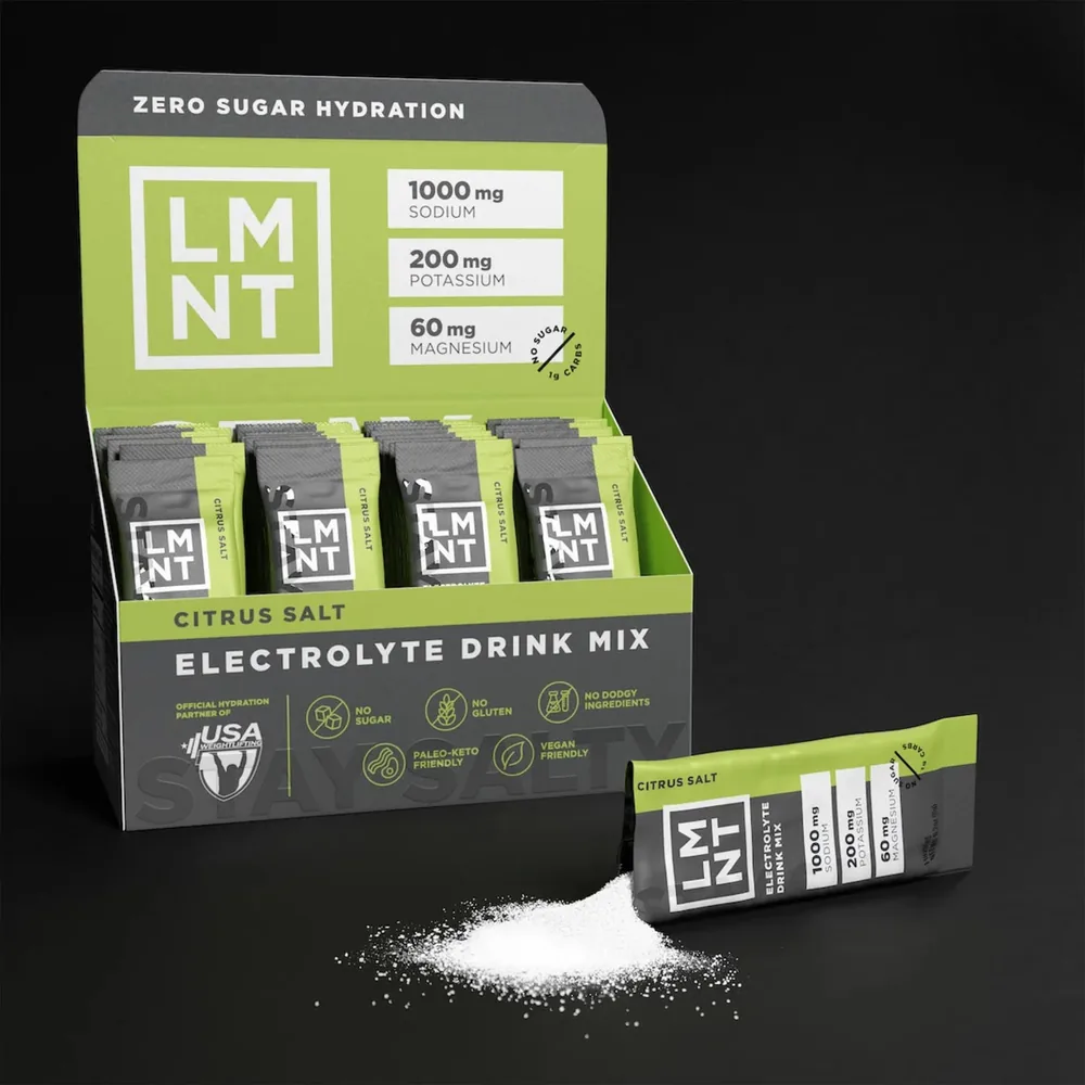 An opened box of LMNT Citrus Salt stick packs beside a small pile of salt