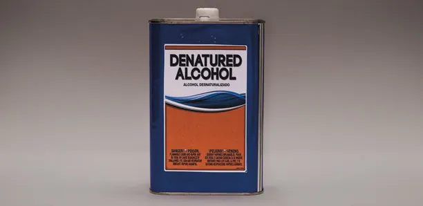 A metal can of denatured alcohol on a gray background.
