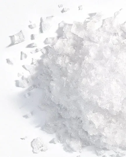 Coarse Dead Sea salt crystals photographed on a white surface.