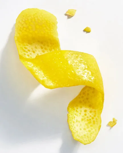 A curled strip of lemon peel on a white surface.