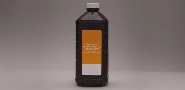 A bottle of hydrogen peroxide on a gray background.