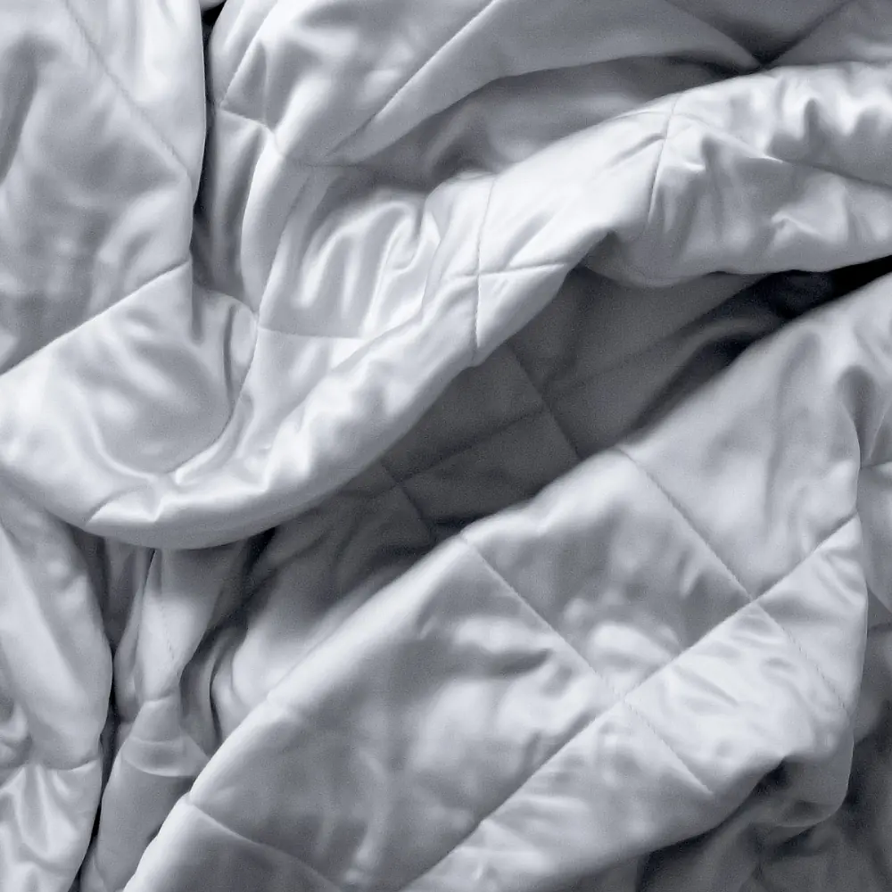 Close view of the soft grey Luxome Lightweight Blanket, its diamond quilting catching the light