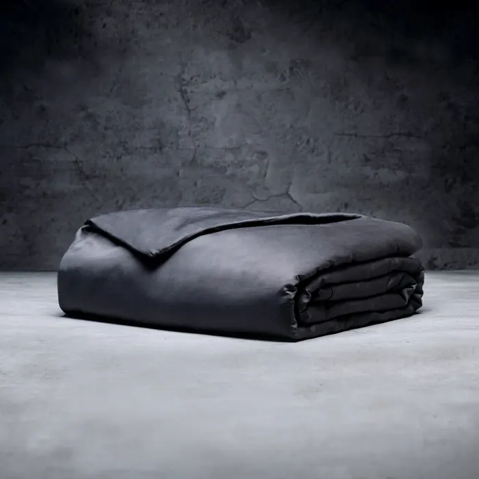The Luxome weighted blanket in all bamboo lyocell, folded on the same concrete floor