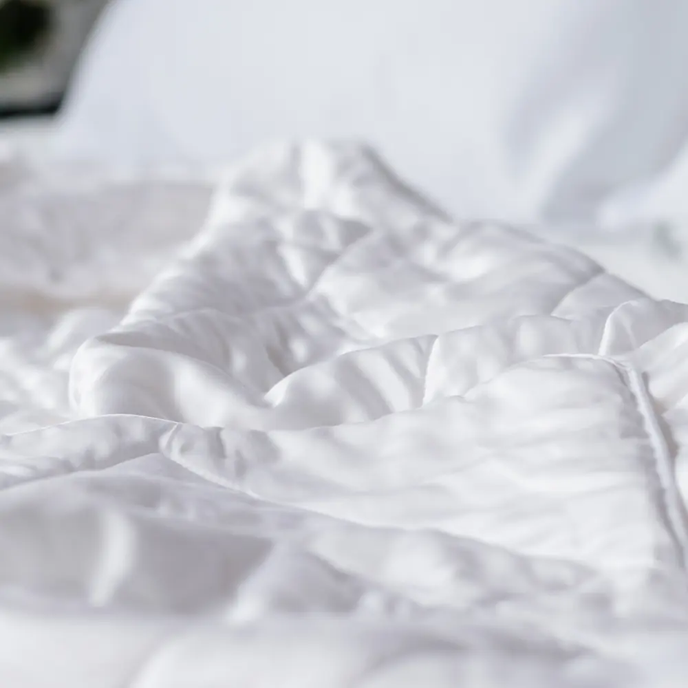 Soft folds of the white Luxome Lightweight Blanket on a bed, seen close up