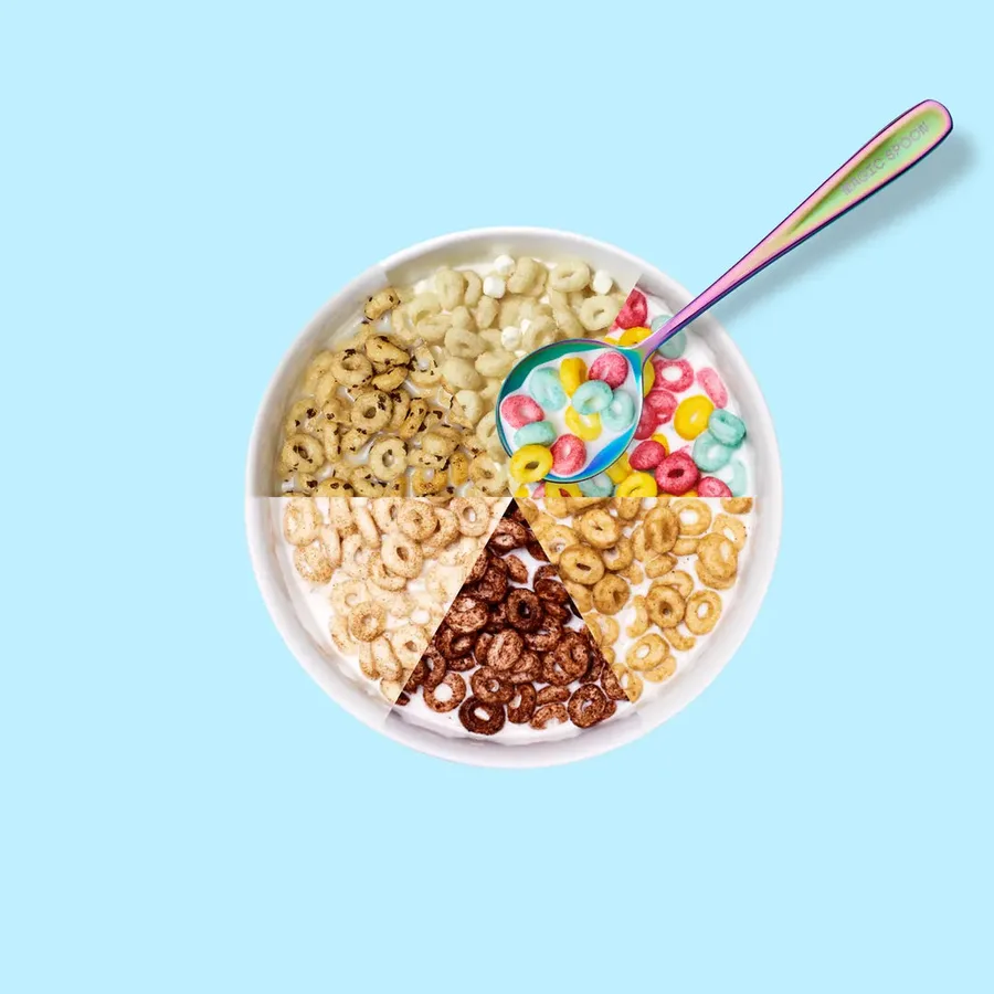 Overhead shot of a white bowl of Magic Spoon cereal divided into six wedges, one for each flavor, on a pale blue background