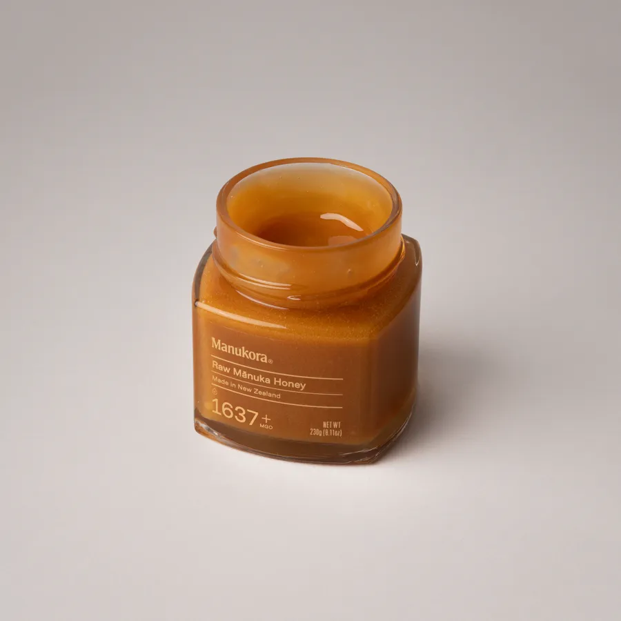 Open jar of Manukora Raw Manuka Honey MGO 1637 plus showing thick amber creamed honey