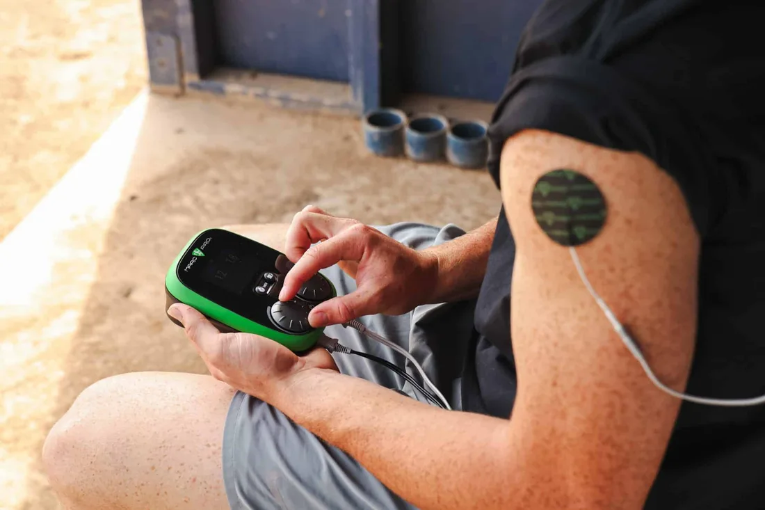 An athlete holding the Marc Pro controller with an electrode on the quad
