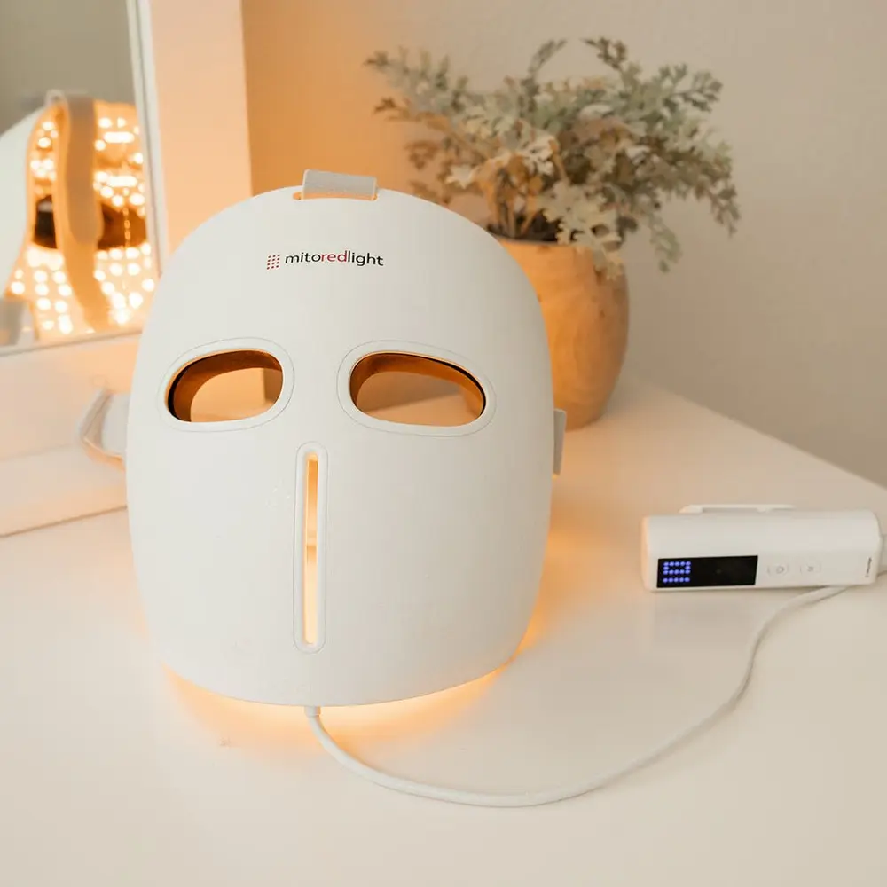 The MitoGLOW mask lit and resting on a bathroom counter