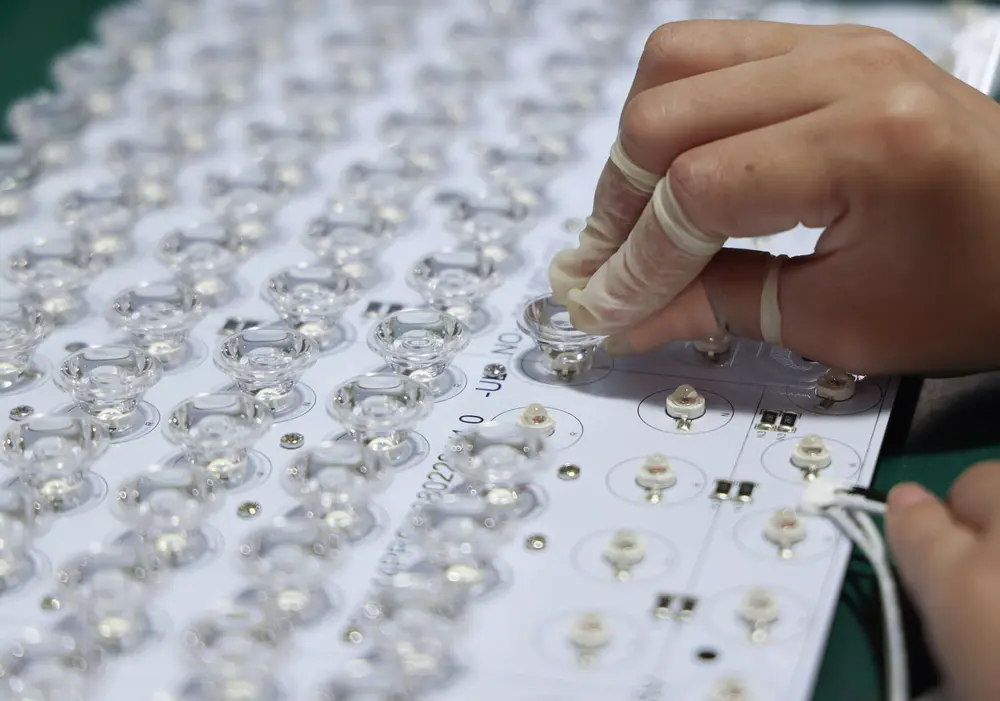 A gloved hand installing an optical lens onto a Mito Red Light LED board
