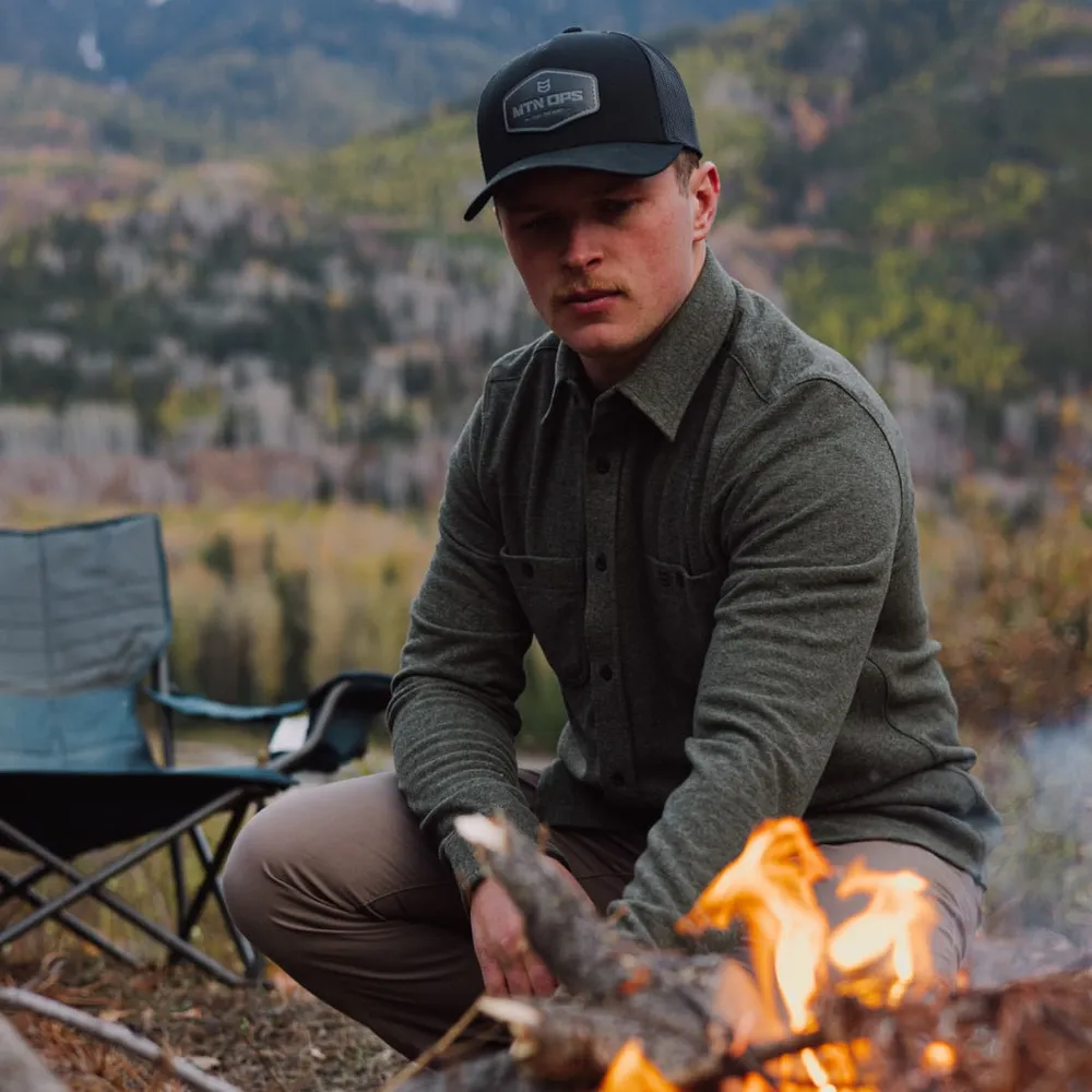 A man building a fire at camp in the evening