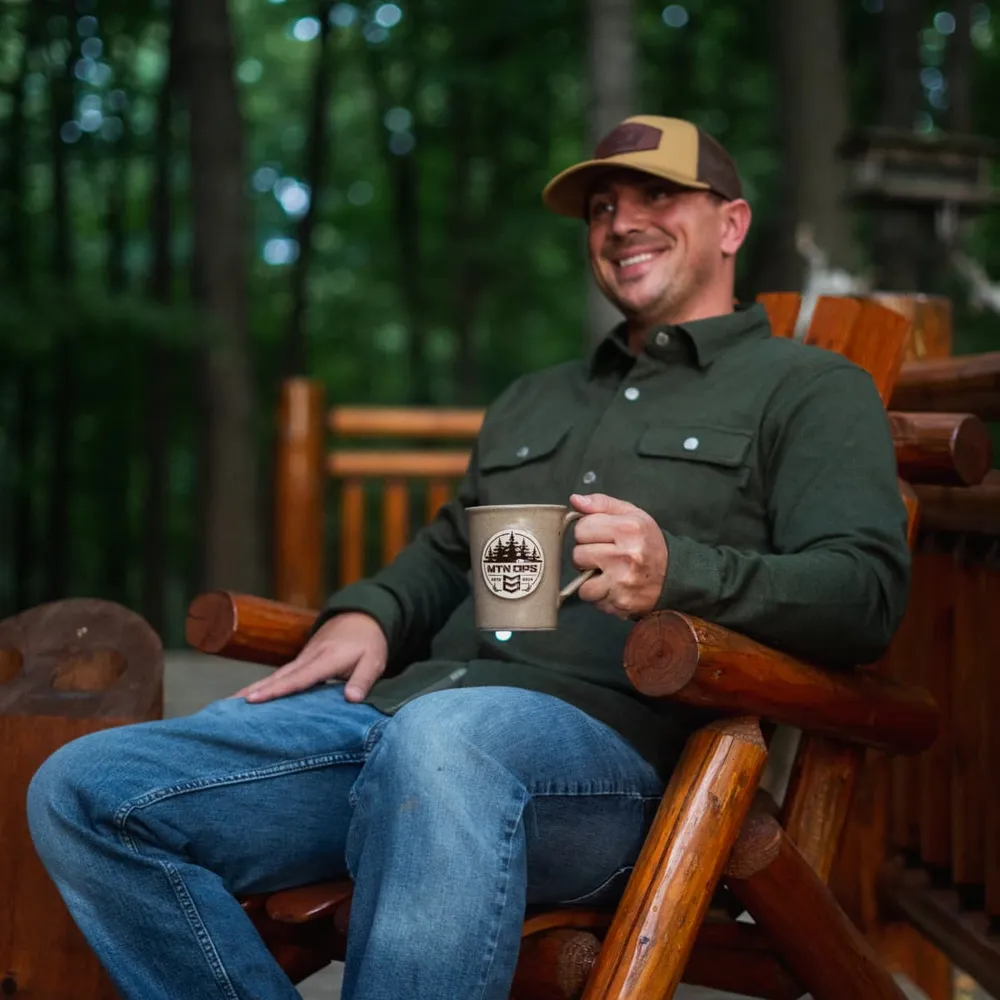 A man sitting on a porch at the end of the day with a drink in hand