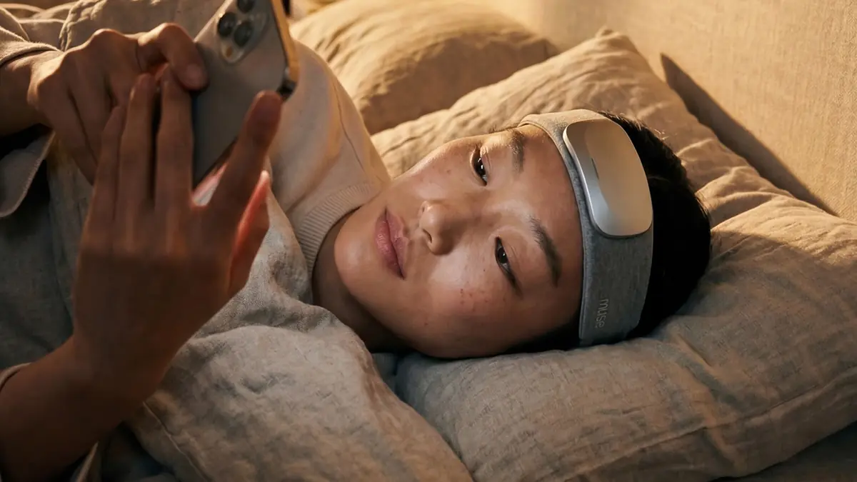 A person asleep on their side on a pillow wearing the Muse headband