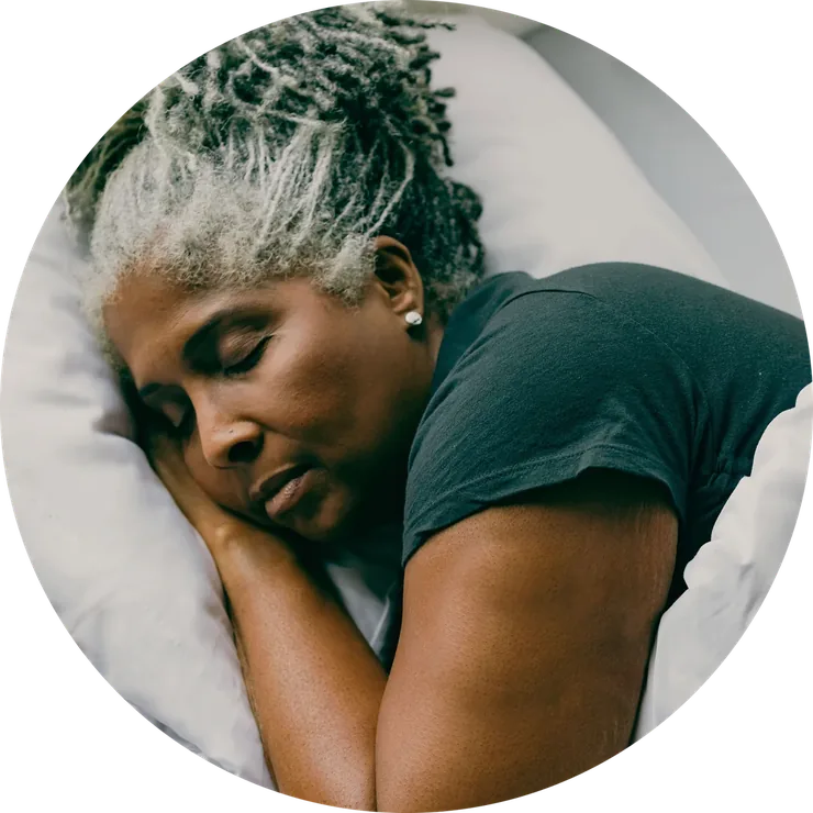 A woman asleep on a pillow, wearing a glucose sensor on her upper arm.