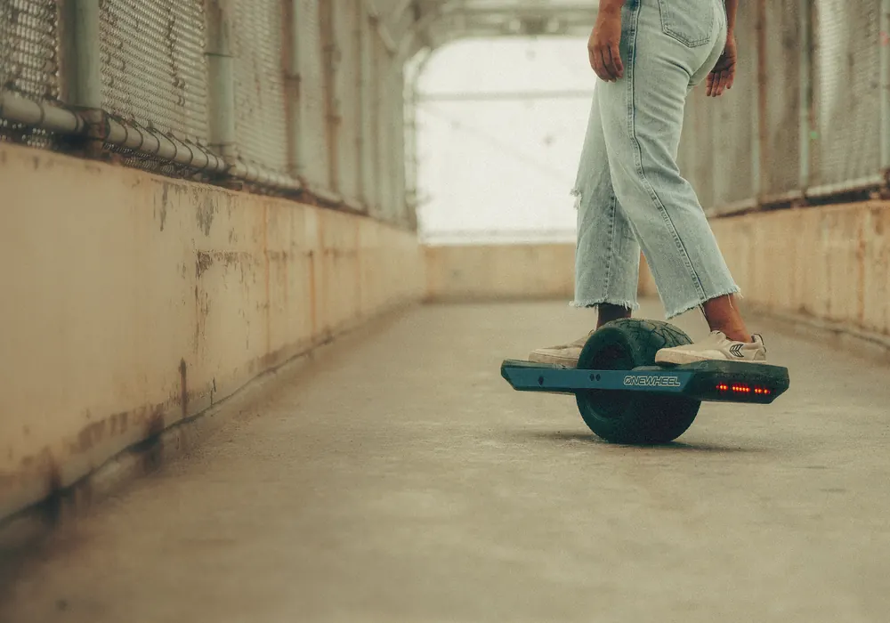 A rider crossing a concrete underpass on a Onewheel.