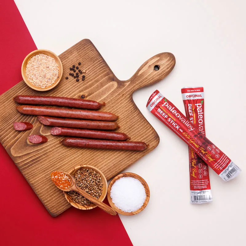 Paleovalley beef sticks on a board with organic spices and salt