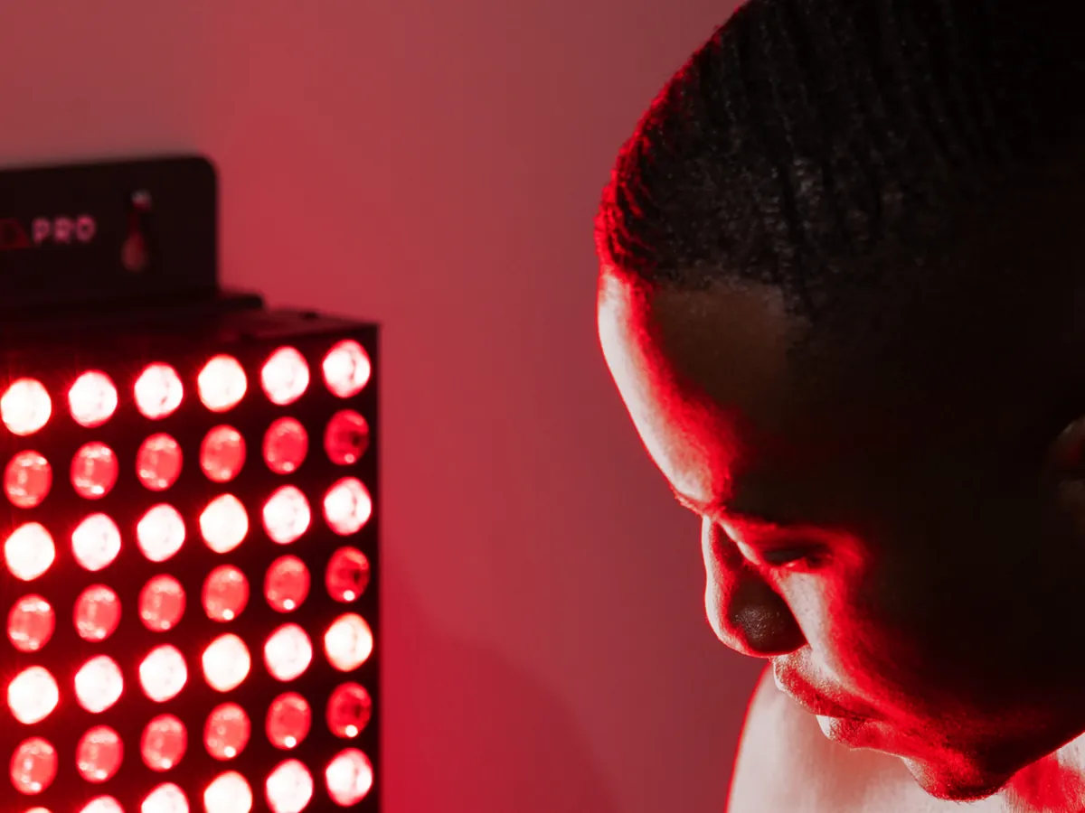 A person seated close to a lit red light therapy panel